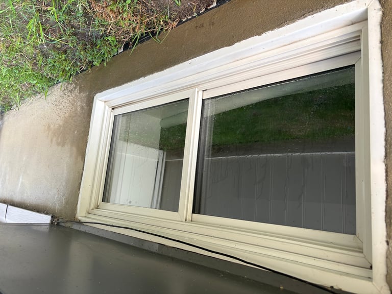 Two-pane horizontal sliding window with white frame and dark screens, dirty before cleaning