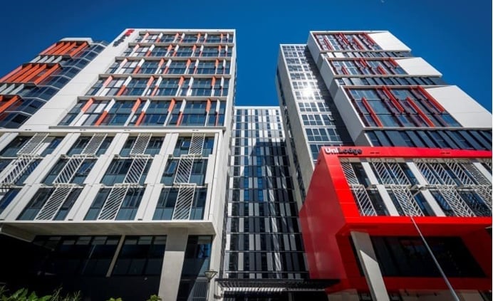 Modern high-rise buildings with colorful facades including red, white, and orange panels against a clear blue sky