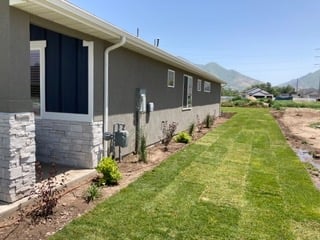 Modern residential townhouses with gray facades, manicured lawn, and mountain views in the background