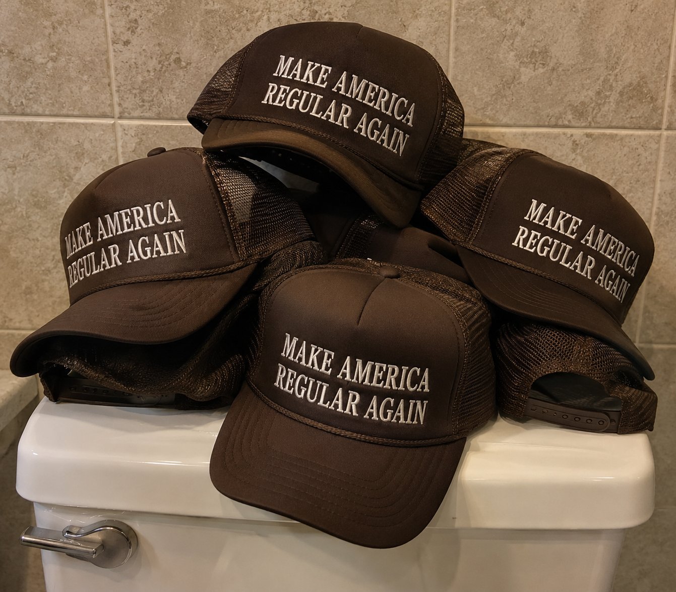 Stack of brown baseball caps with Make America Regular Again text printed on them, arranged on a bathroom toilet.