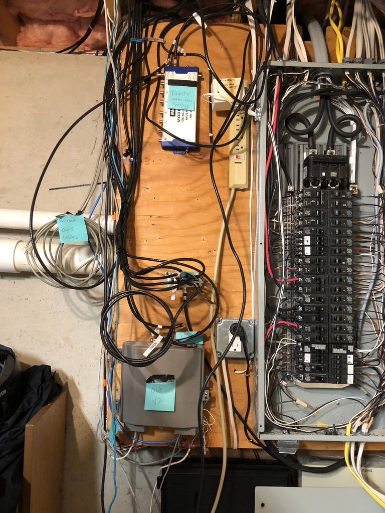 Electrical panel and wiring installation with circuit breaker box, cables, and connected devices on wooden board
