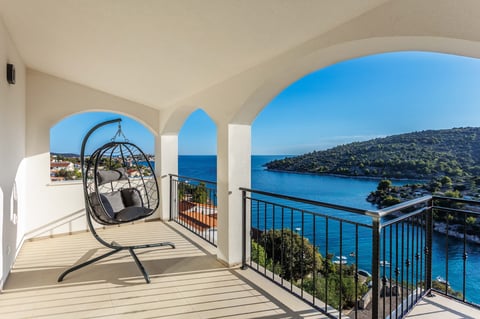 Hanging egg chair on modern white balcony overlooking the Adriatic