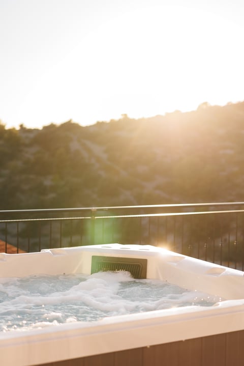 Hot tub with bubbling water on a deck overlooking rolling hills during golden hour sunset