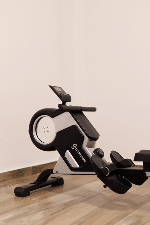 Black and white stationary exercise bike with digital display on wooden floor against beige background