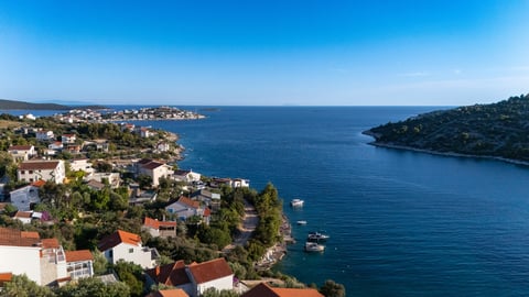Aerial view of Sevid village with white and terracotta buildings nestled along a blue sea inlet