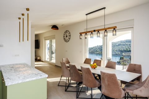 Modern dining room with brown leather chairs, white table, pendant lights, and large windows overlooking mountains