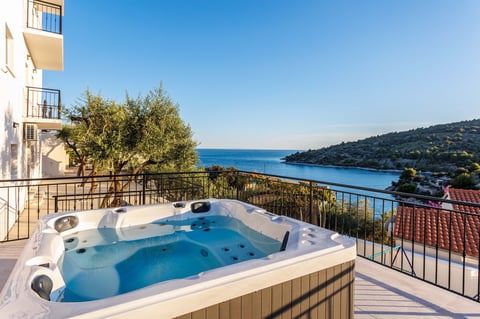 Hot tub on a terrace overlooking a Mediterranean coastal town and blue sea
