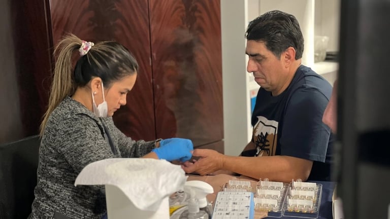 Woman wearing blue gloves receives a medical test or vaccine from a man in a dark shirt at an indoor clinic