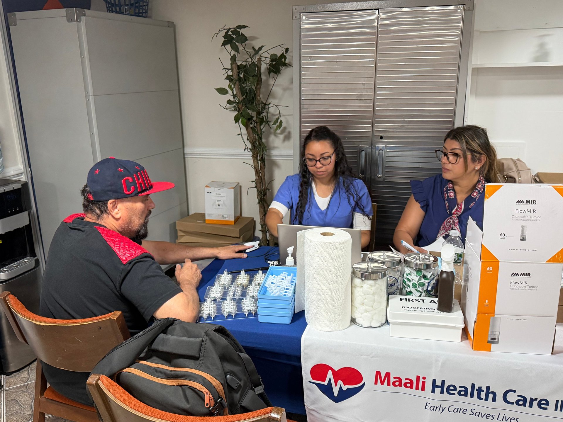 Maali Health Care clinic worker discusses supplies with patient at table