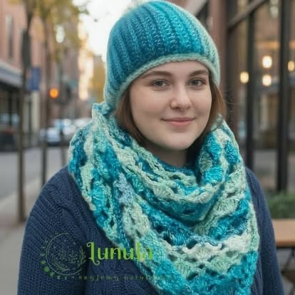 Young woman wearing a teal knit beanie and patterned scarf on an urban street