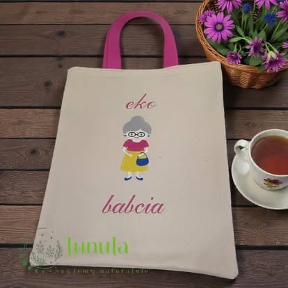 Cream canvas tote bag with pink handles featuring illustration of child and text eke, babcia, and lunula