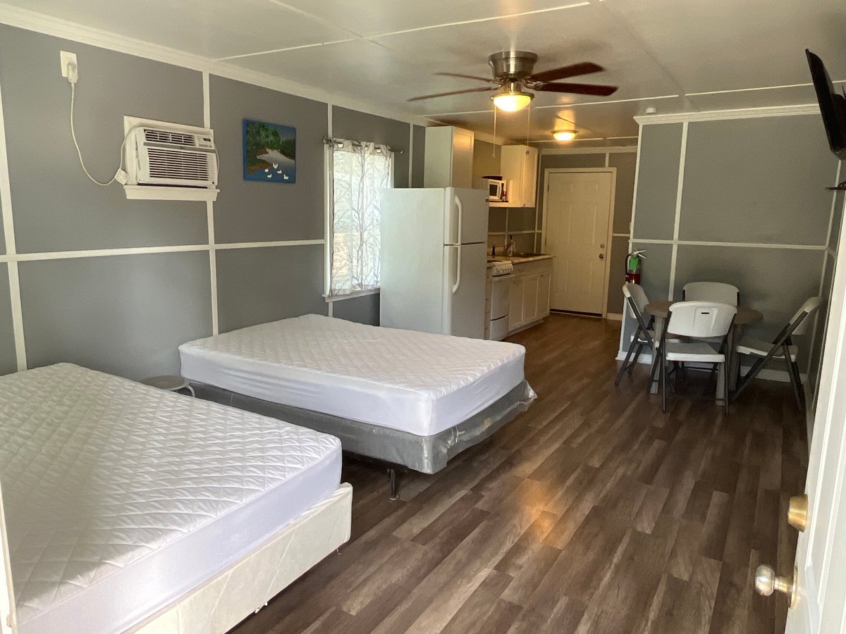 Cabin interior with two single beds, ceiling fan, and kitchenette in the background