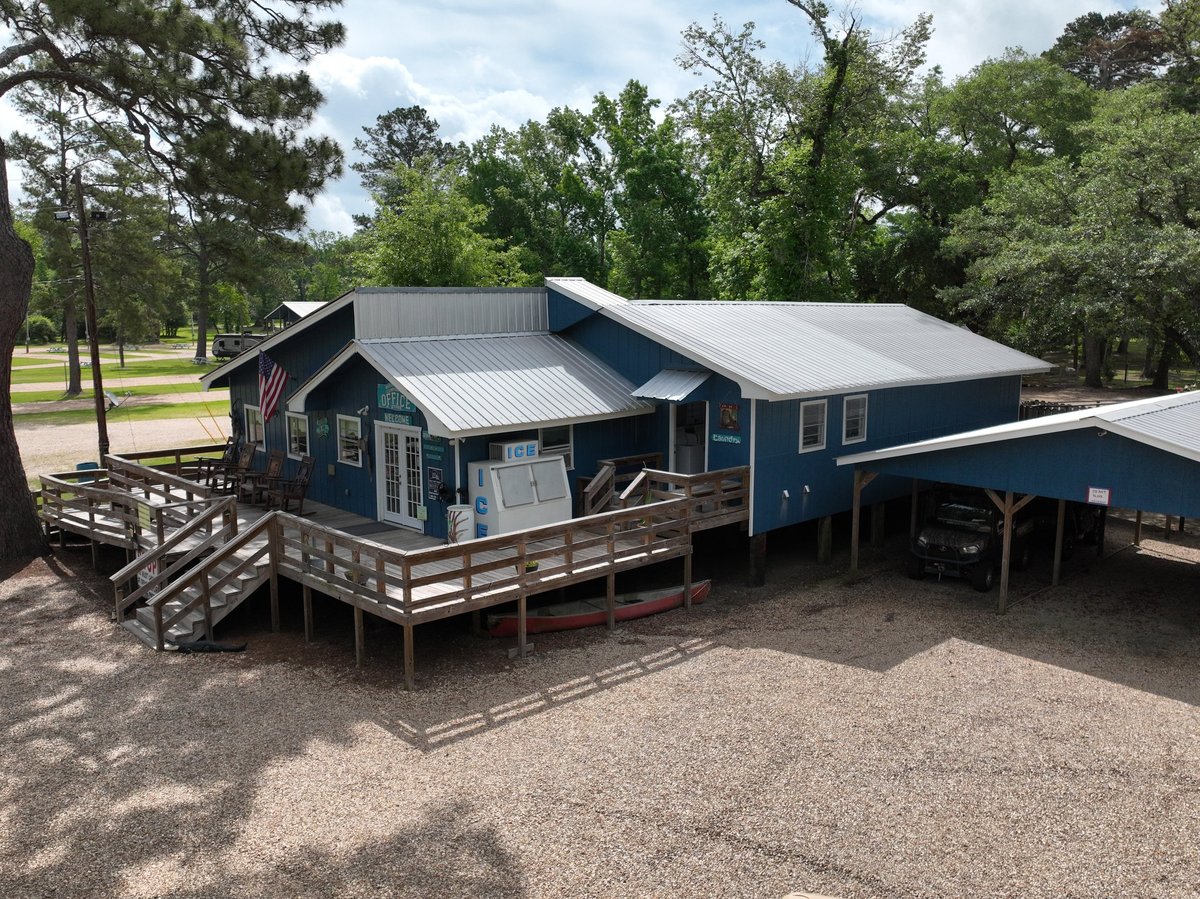 Blue modern barn-style house with metal roof and wooden deck surrounded by trees