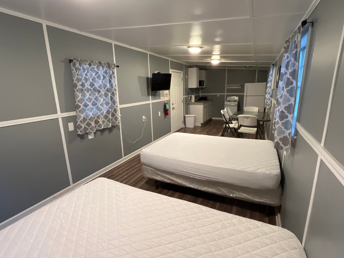 Two twin beds in a modern mobile home bedroom with gray and white paneled walls and patterned curtains