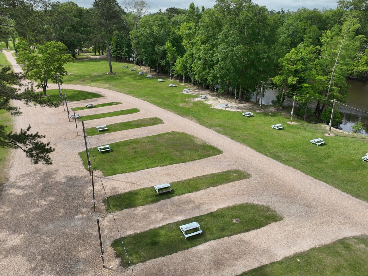 Aerial view of RV parking lot with grass-lined spaces surrounded by trees