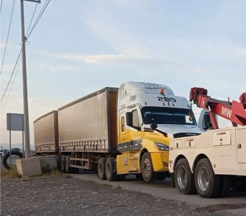Grúa amarilla y blanca asistida por unidad roja de GRUPO MW en carretera