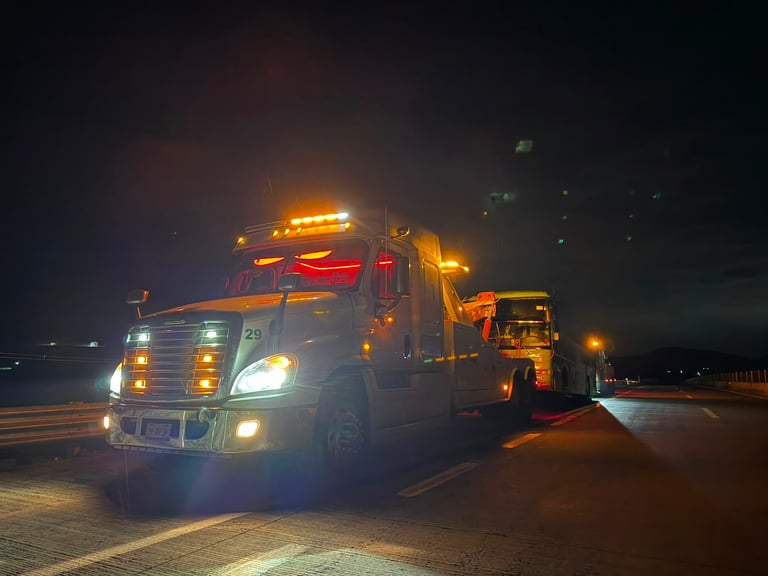 Grúa con luces rojas y amarillas trabajando en carretera de noche