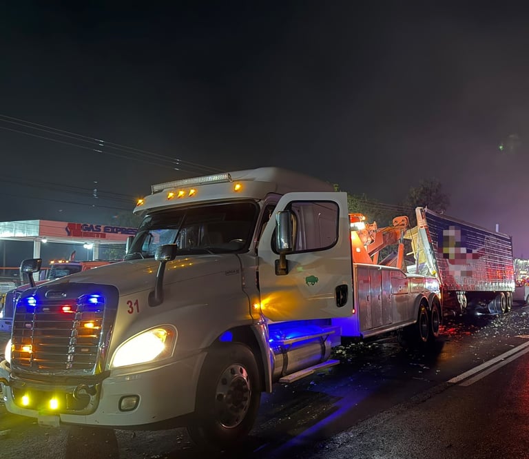 Camión comercial blanco con luces de emergencia azules y amarillas en carretera nocturna