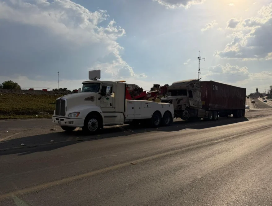 Grúa pesada recuperando trailer siniestrado en carretera