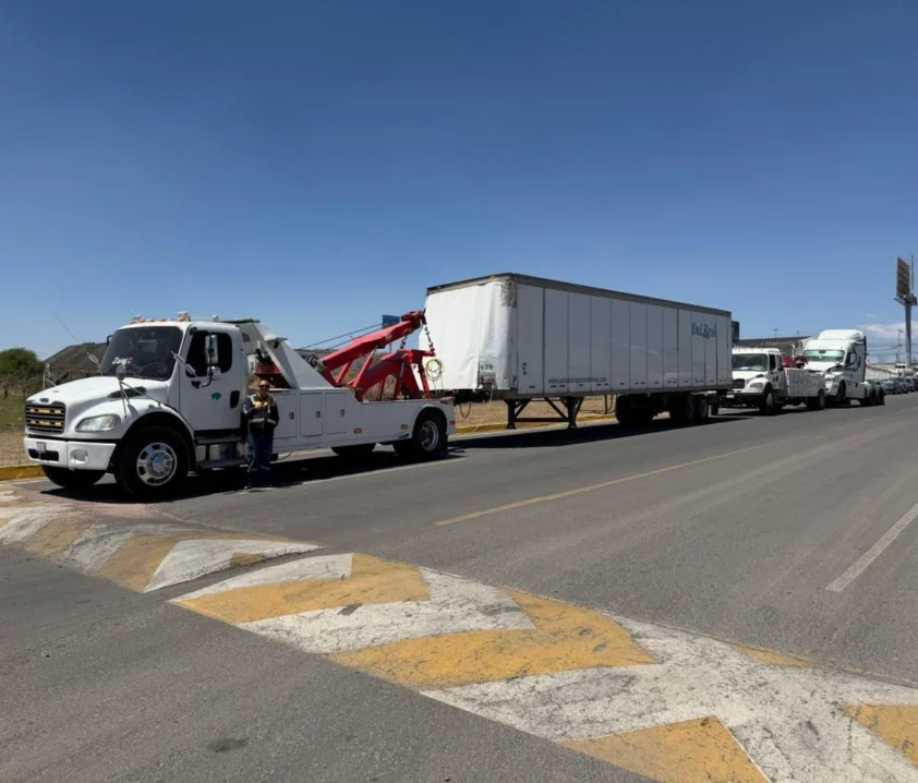 Grúa blanca de GRUPO MW trasladando caja seca en carretera