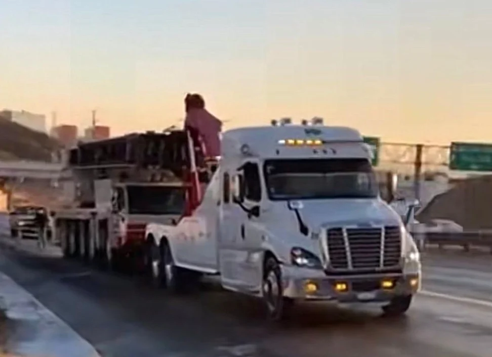 Transportes MW Freightliner trasladando maquinaria industrial en plataforma al atardecer