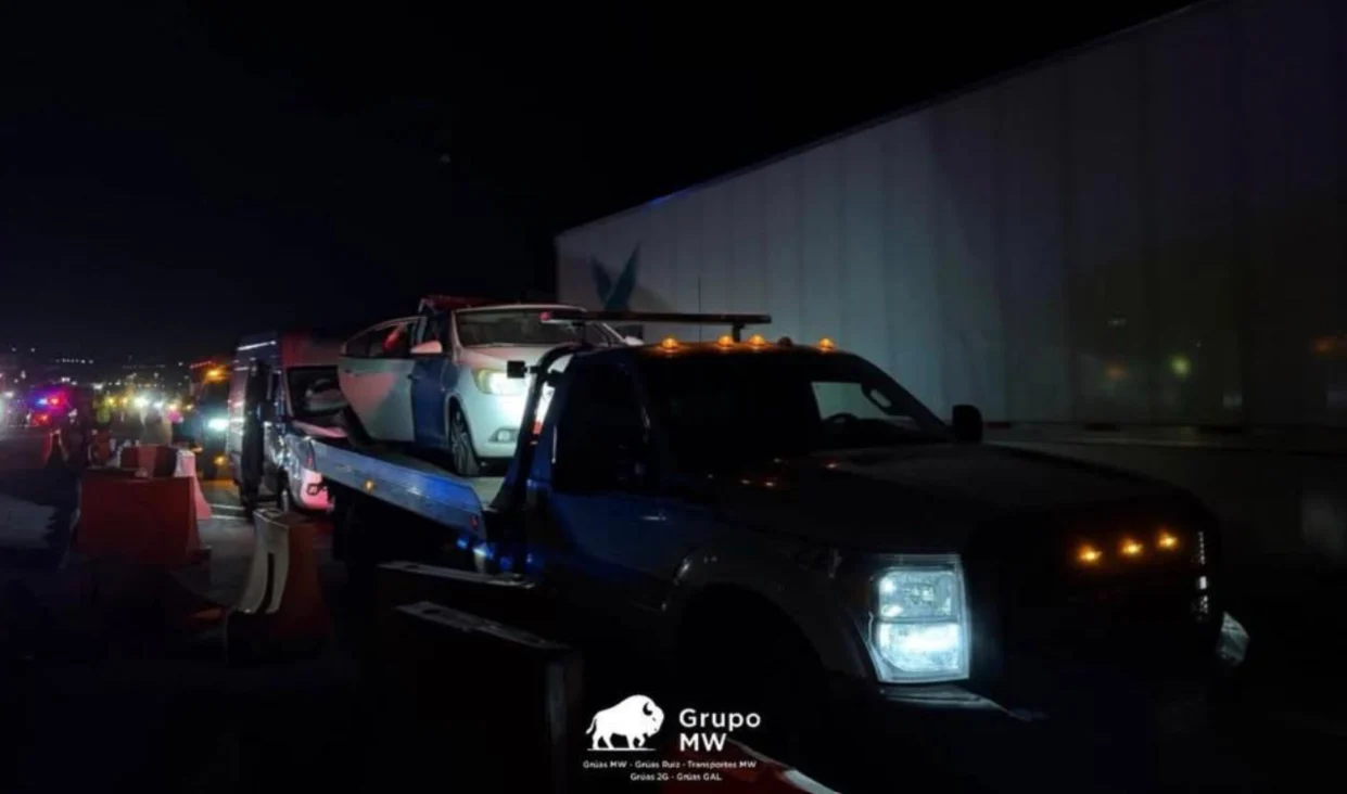 Grúa ligera GRUPO MW con luces de emergencia trasladando vehículo de noche