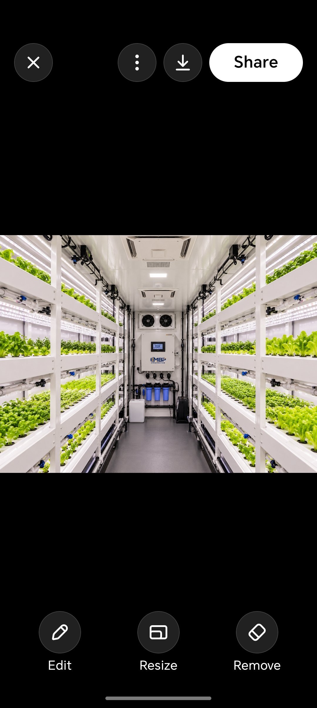 Interior of vertical farming container with rows of green plants on white shelving racks and control systems at center