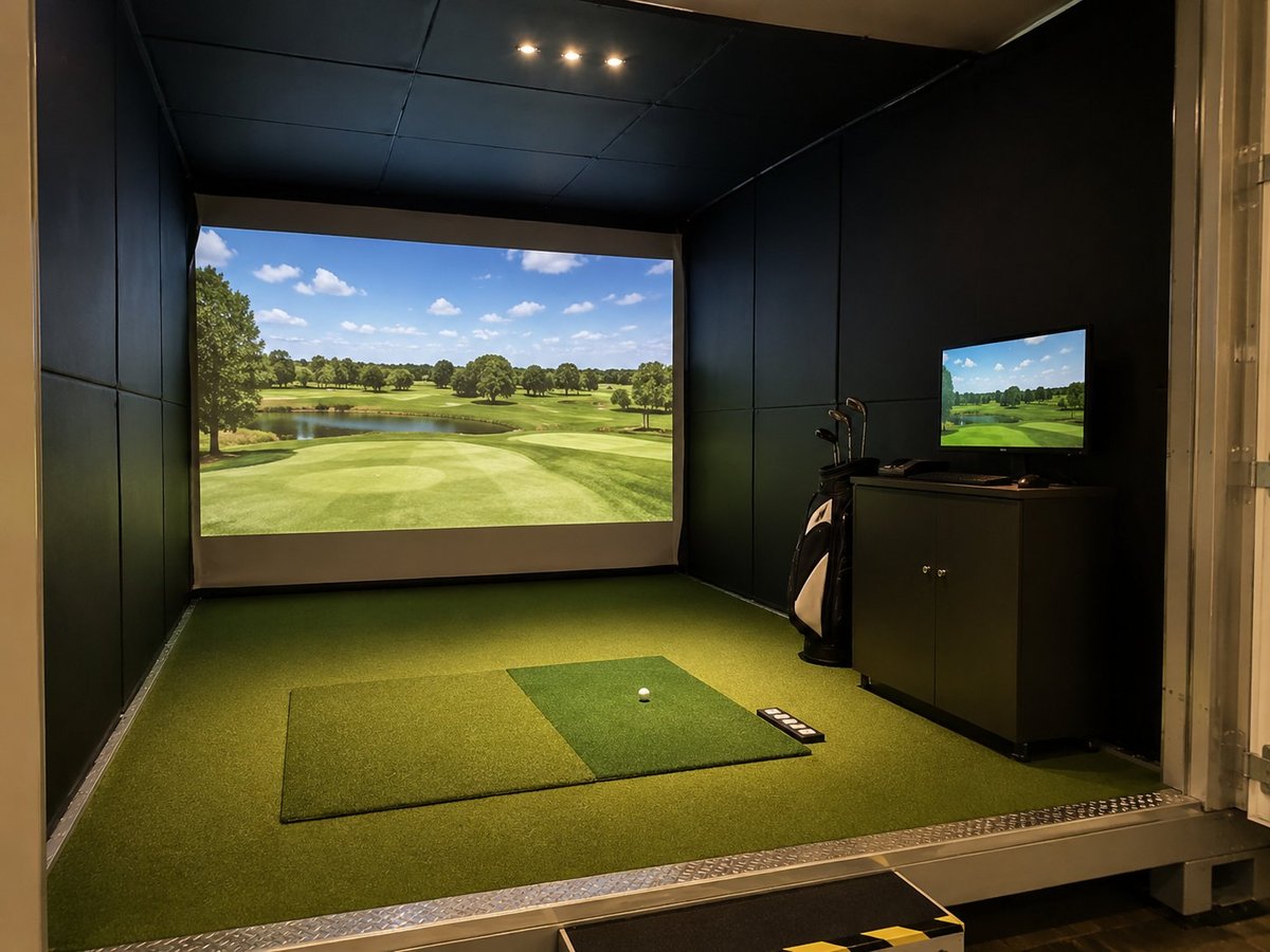 Indoor golf simulator room with large display screen, putting mat, ball, and small monitor on dark walls