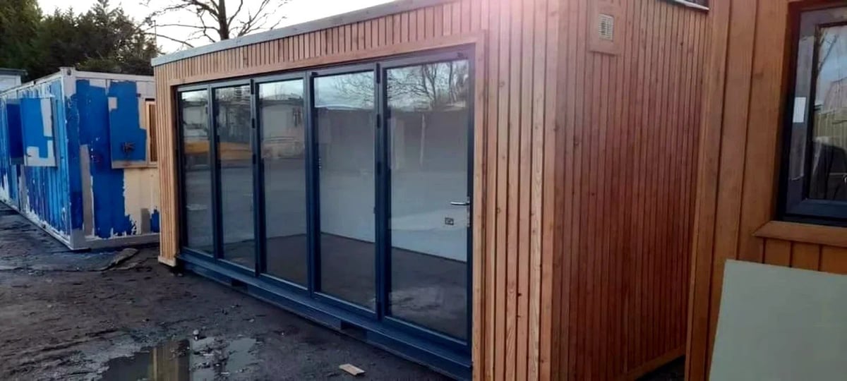 Modern modular building with large black-framed windows and brown corrugated metal cladding on exterior