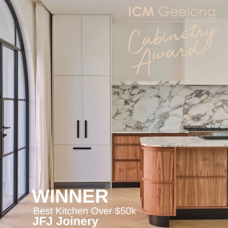 Modern kitchen with white cabinetry, marble backsplash, curved wooden island, and black metal framed window — JFJ Joinery award-winning work