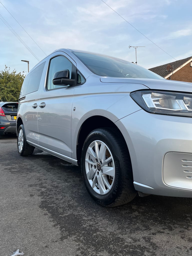 Silver Volkswagen Caddy compact van parked in a driveway with white alloy wheels