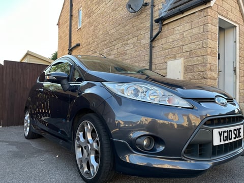 Black Ford Fiesta parked in front of a brick house with alloy wheels and UK license plate