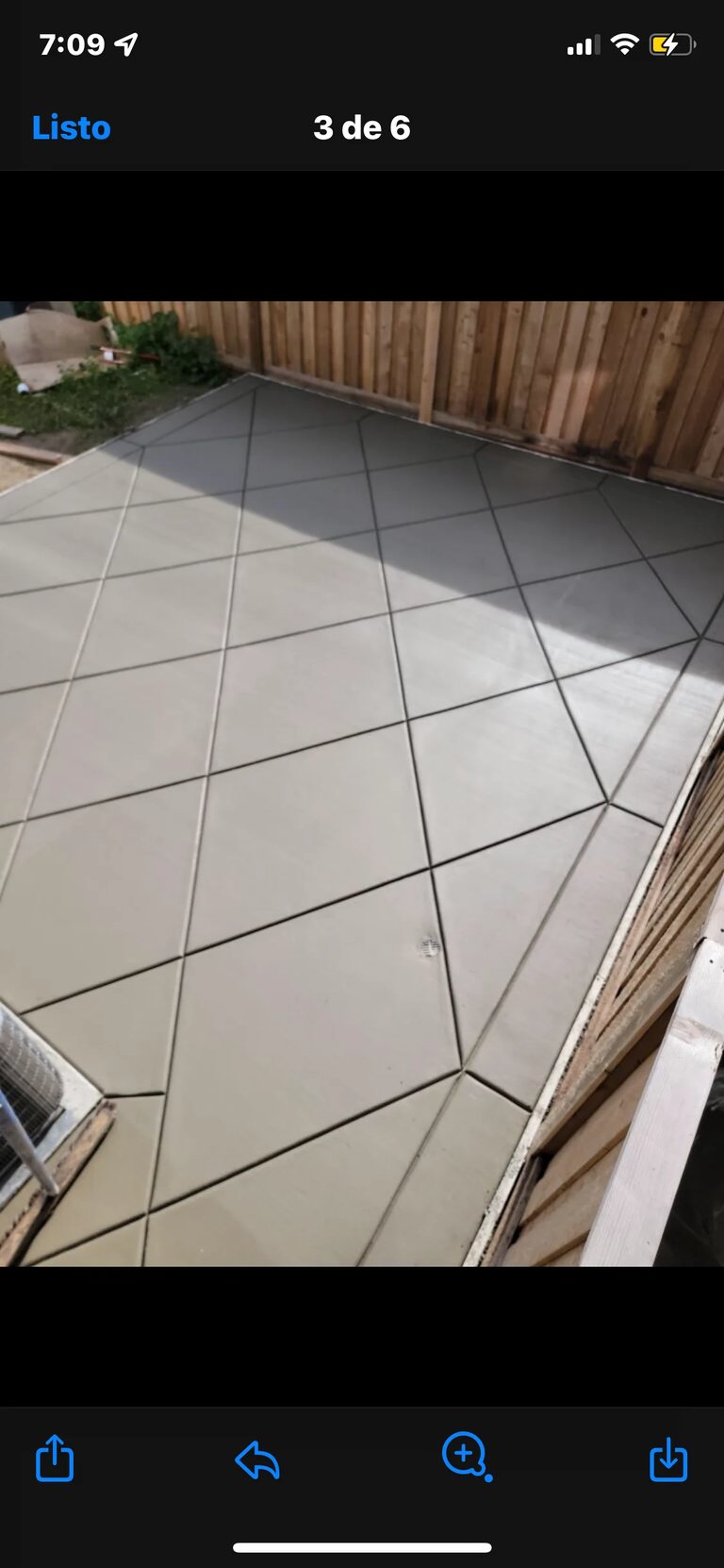 Diamond-pattern stamped concrete patio with wooden fence background