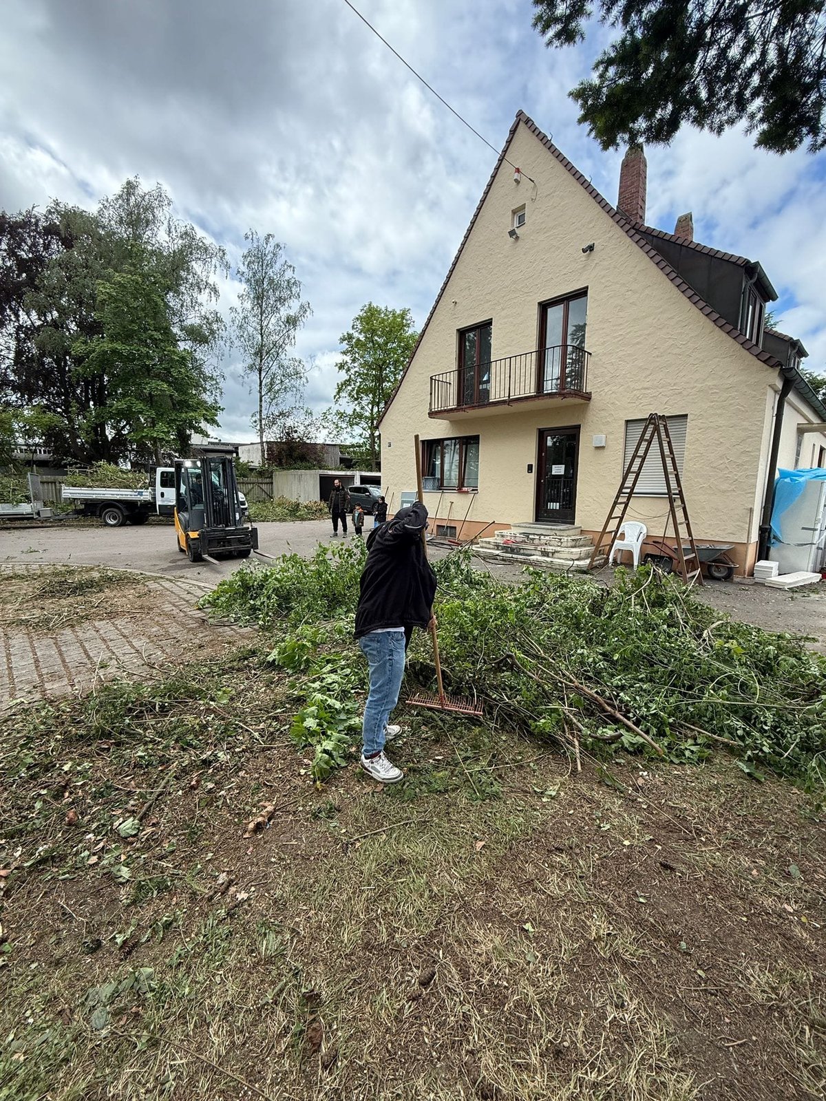 Haus mit Garten während einer Renovierung, mit Rechen und Schubkarre im Vorgarten — M☆K König Hausmeisterservice