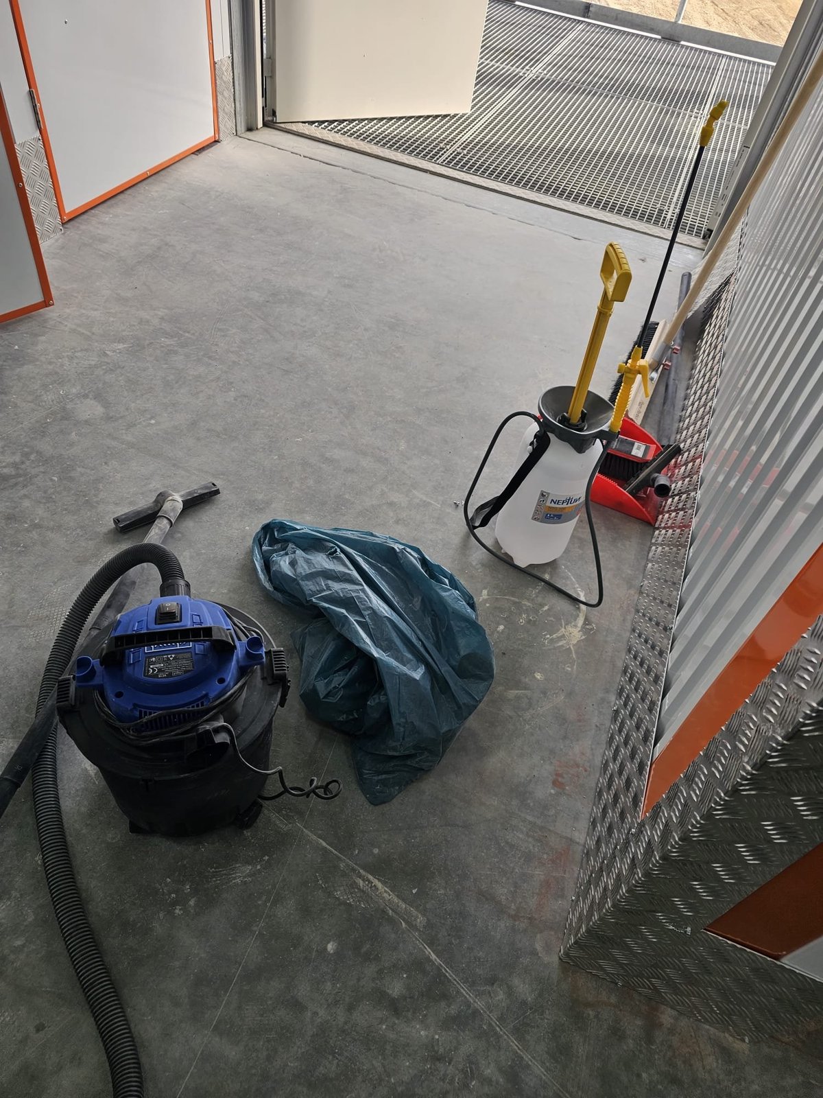 Reinigungsgeräte mit Sauger, Sprühgerät und Werkzeug auf Betonboden bei der Garagenreinigung — M☆K König Hausmeisterservice