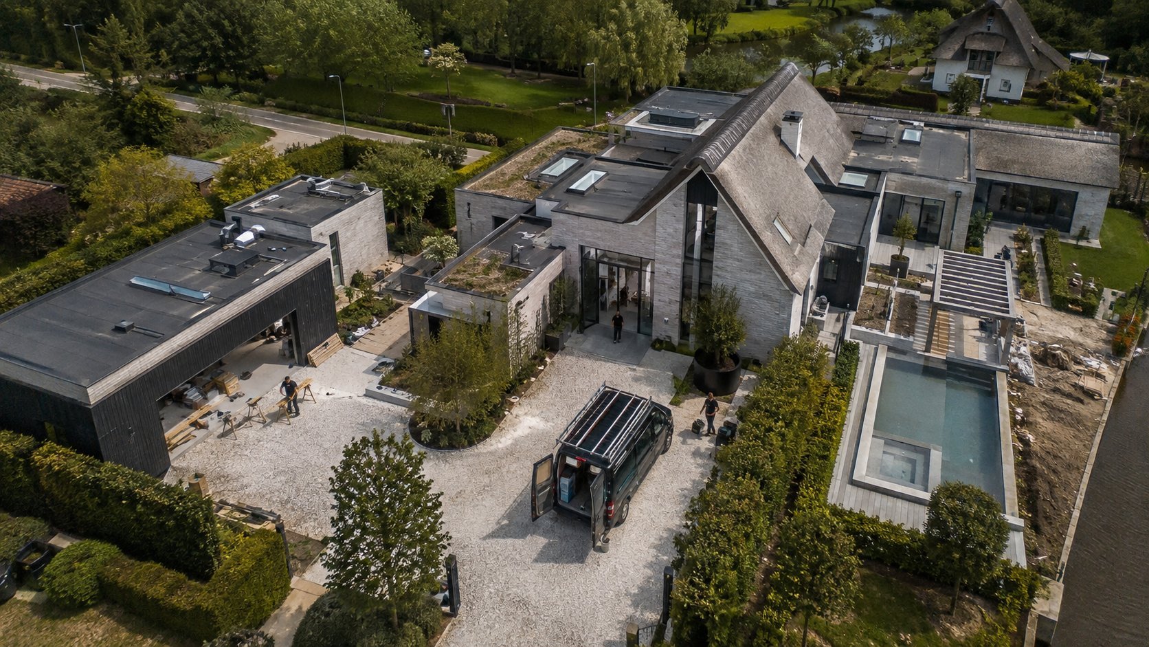 Aerial view of modern residential property with solar panels, patio area, and swimming pool surrounded by landscaping