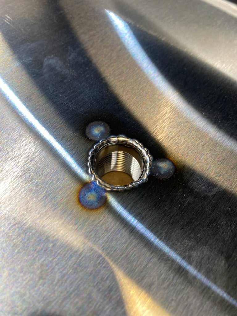 Close-up of a metal screw valve mounted on a brushed steel surface, showing precision CNC plasma cutting work