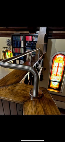 Interior staircase with metal railings, wooden steps, and bookshelves visible in the background with a decorative light fixture