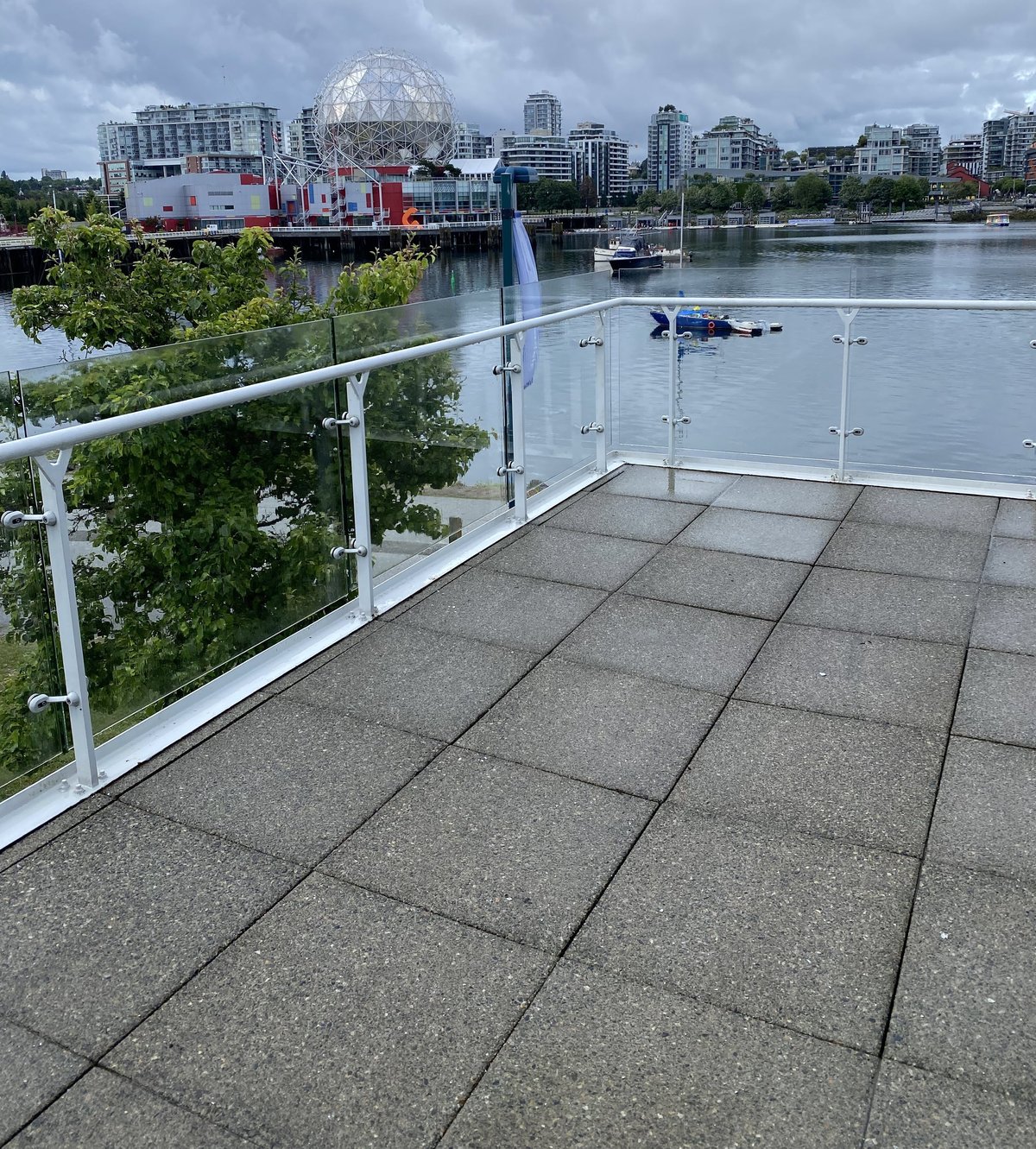 Waterfront deck overlooking Vancouvers False Creek with the geodesic dome, downtown skyline, boats, and surrounding buildings visible across the water