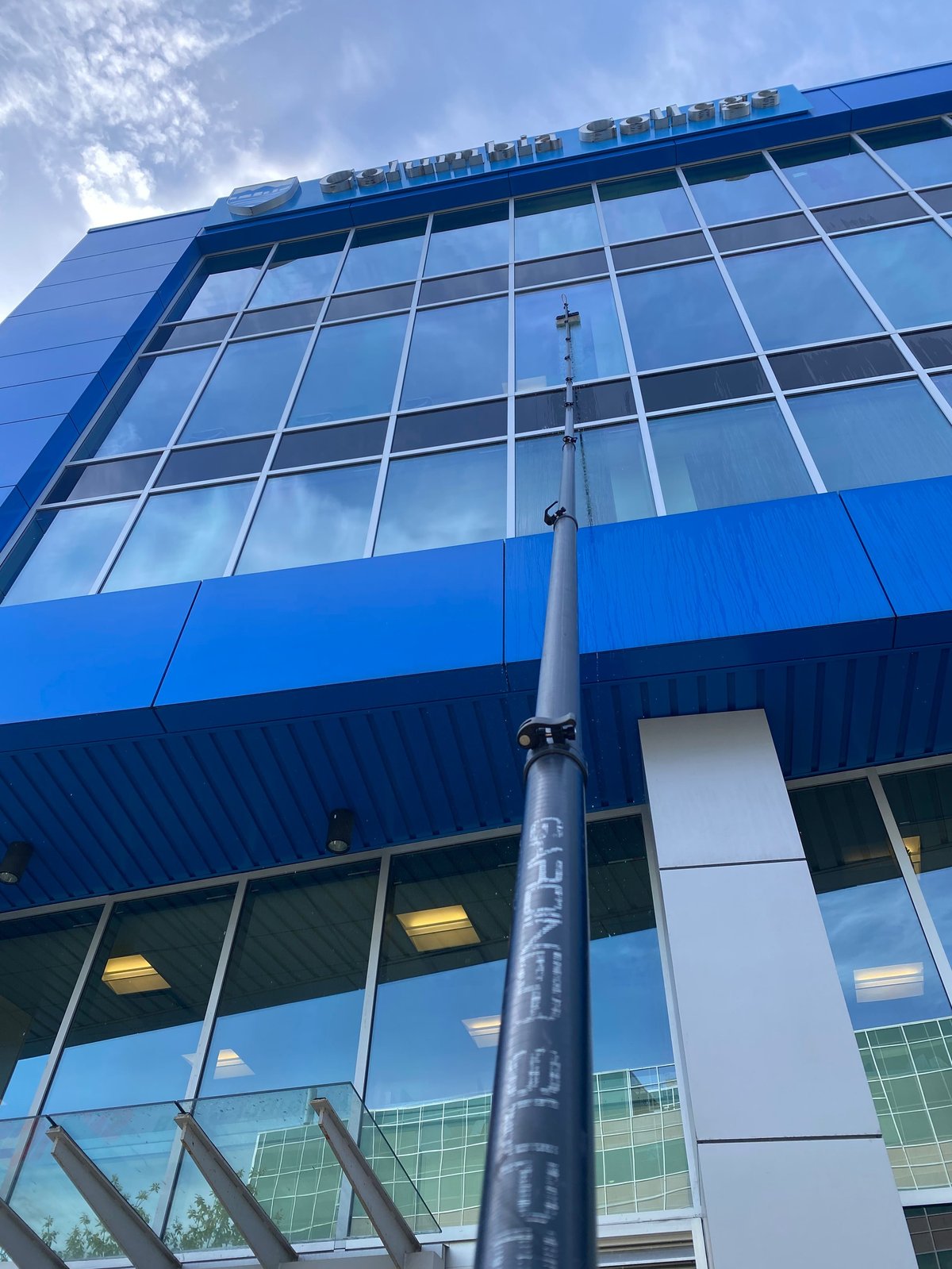 Modern blue and glass building exterior with large windows and metal utility pole against blue sky