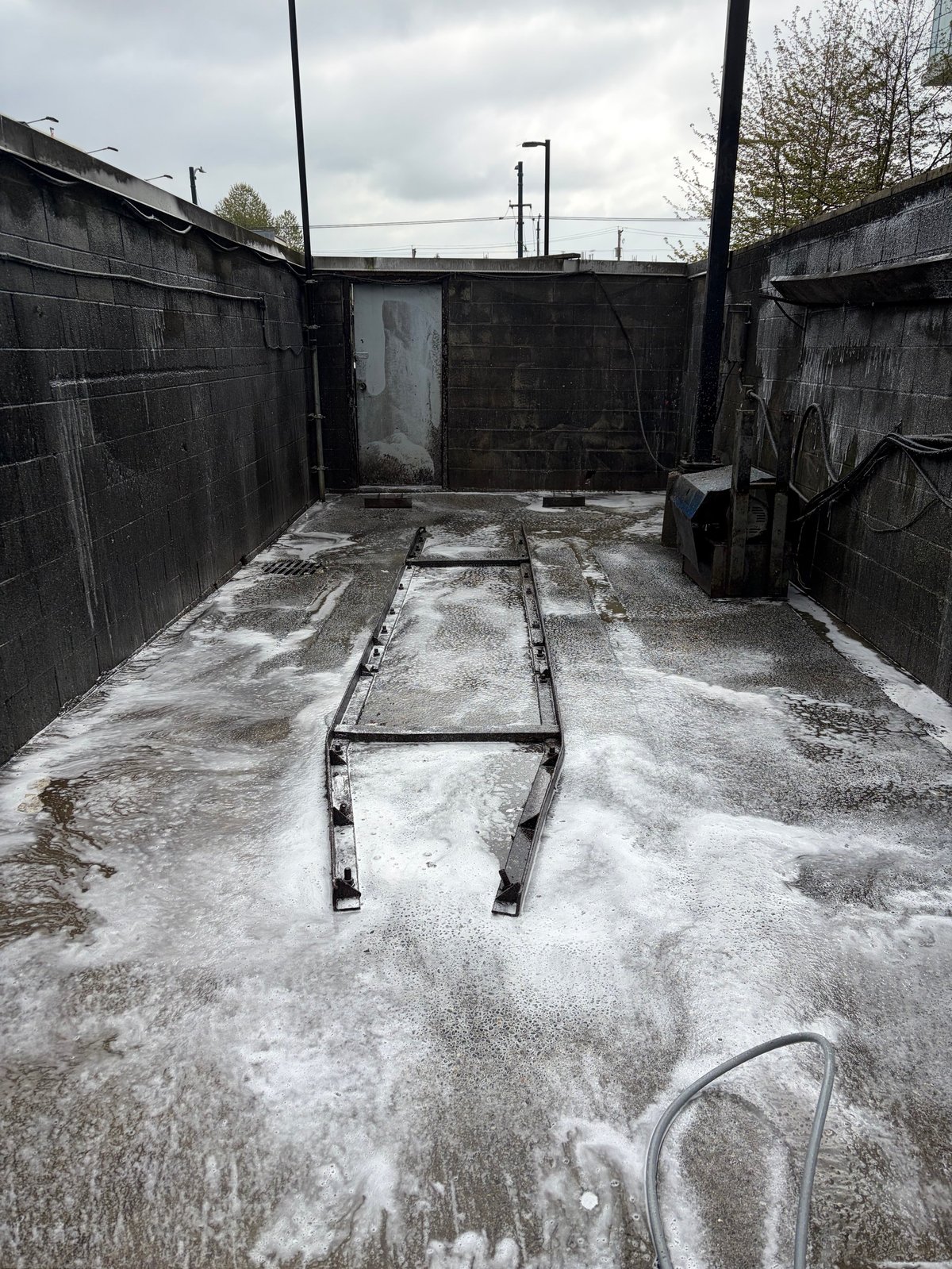 Empty boat trailer in concrete slipway with mossy walls and overcast sky