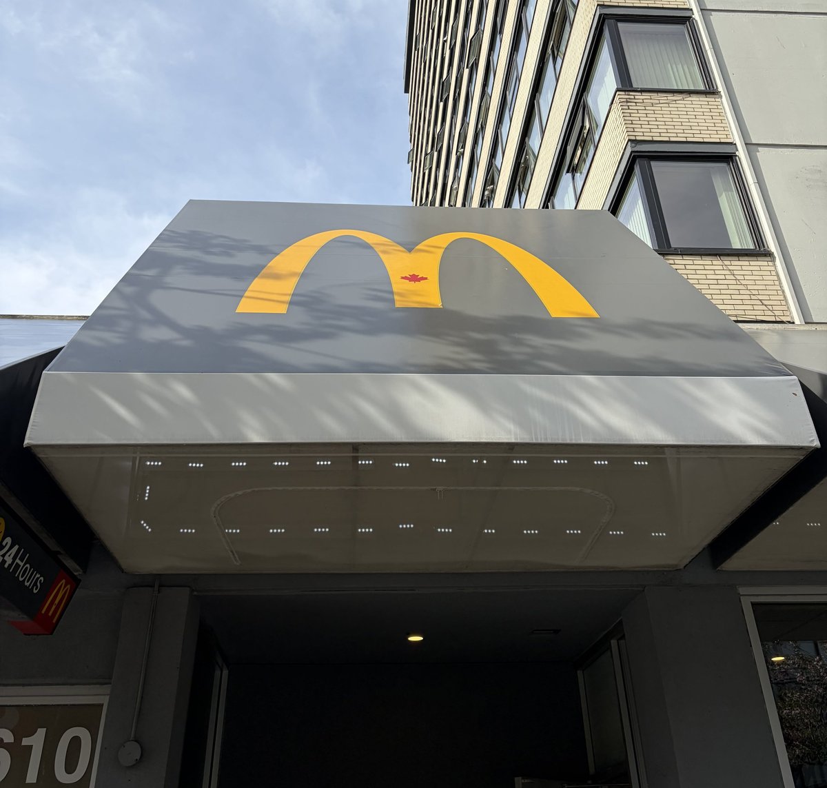 McDonalds golden arches logo on storefront awning with modern building facade above