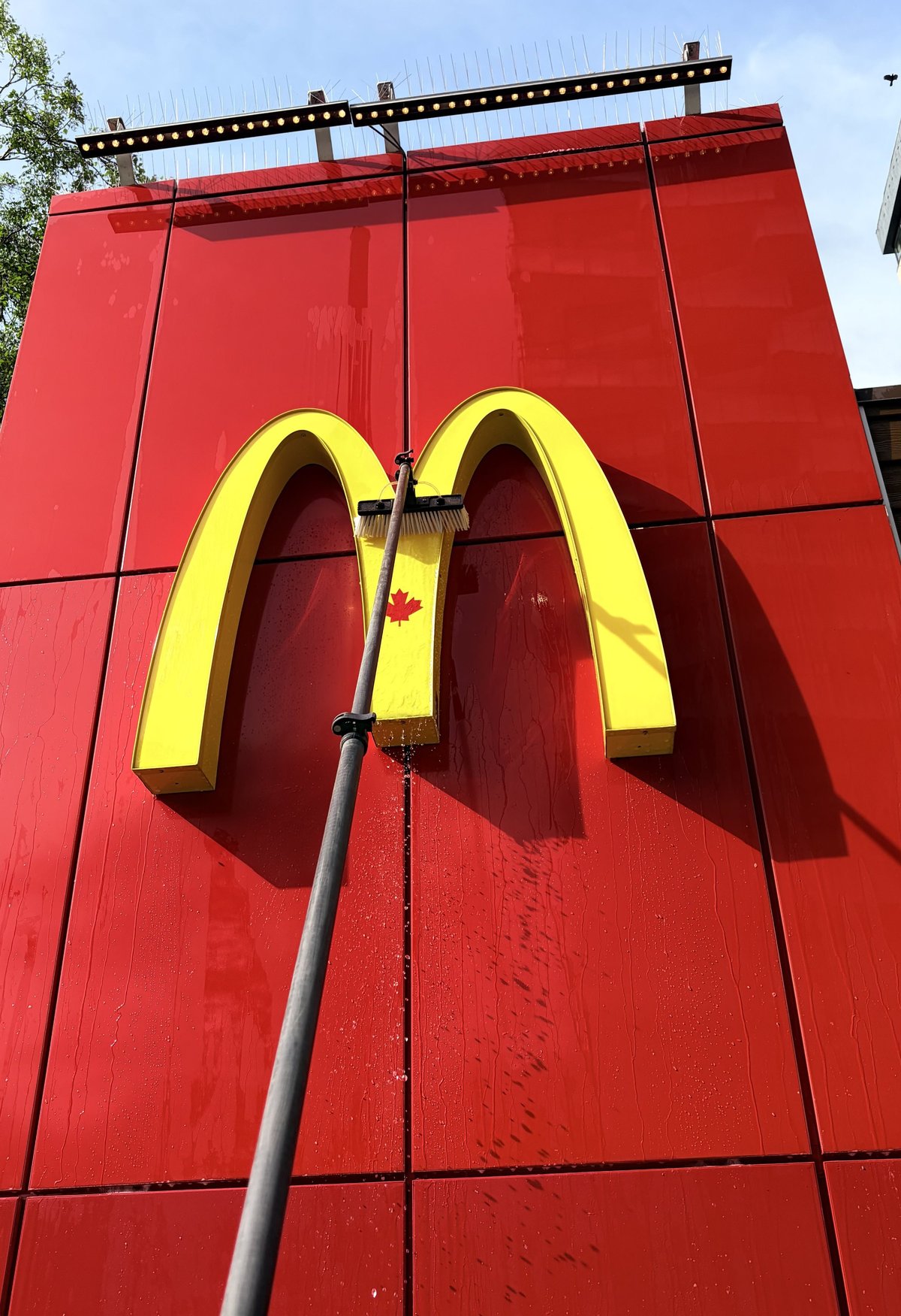 Golden arches McDonalds logo mounted on a red wall with metal framework overhead