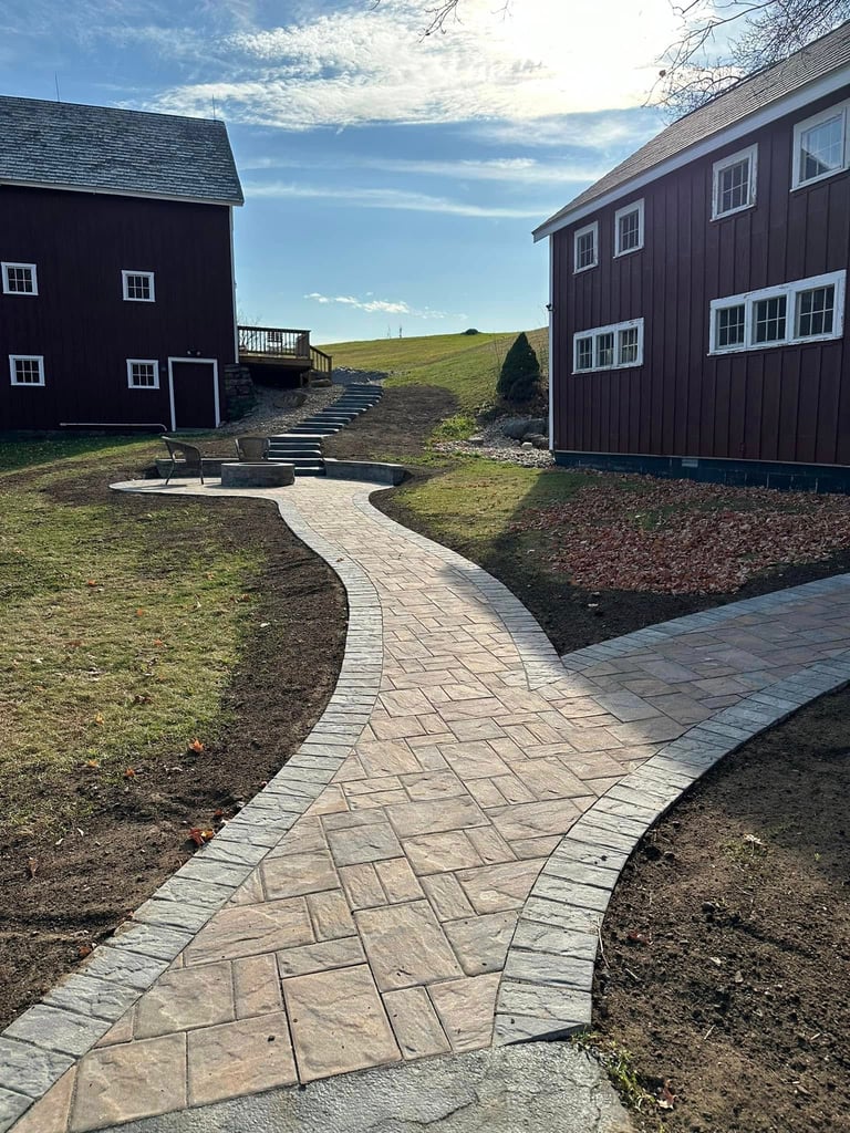Curved paver pathway between barn buildings