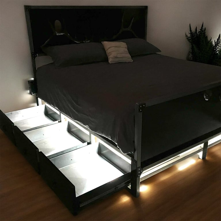 Modern black platform bed with storage drawers and LED lighting, topped with black bedding and decorative pillows