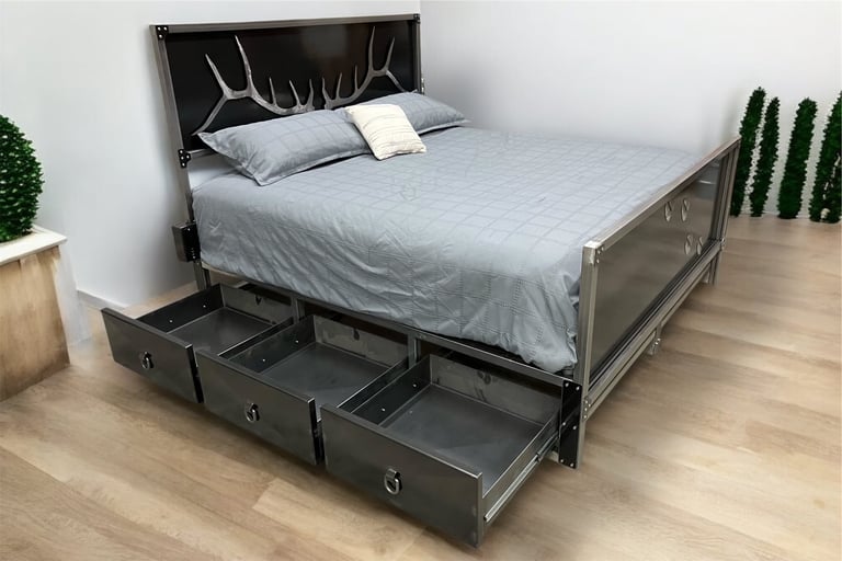 Modern bed frame with antler-themed headboard, blue bedding, and three pull-out storage drawers underneath, flanked by potted plants