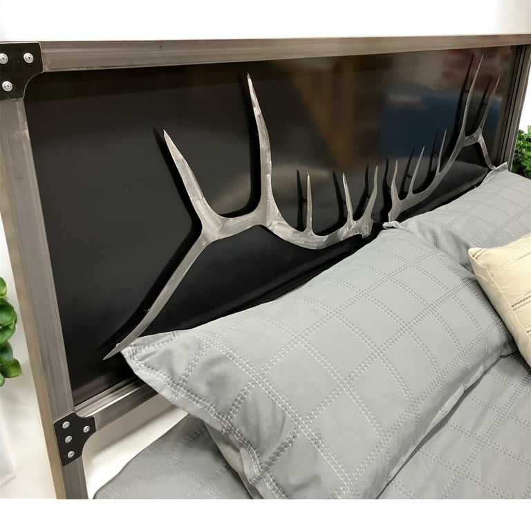 Decorative large deer antler headboard on a bed with gray quilted pillows and white linens