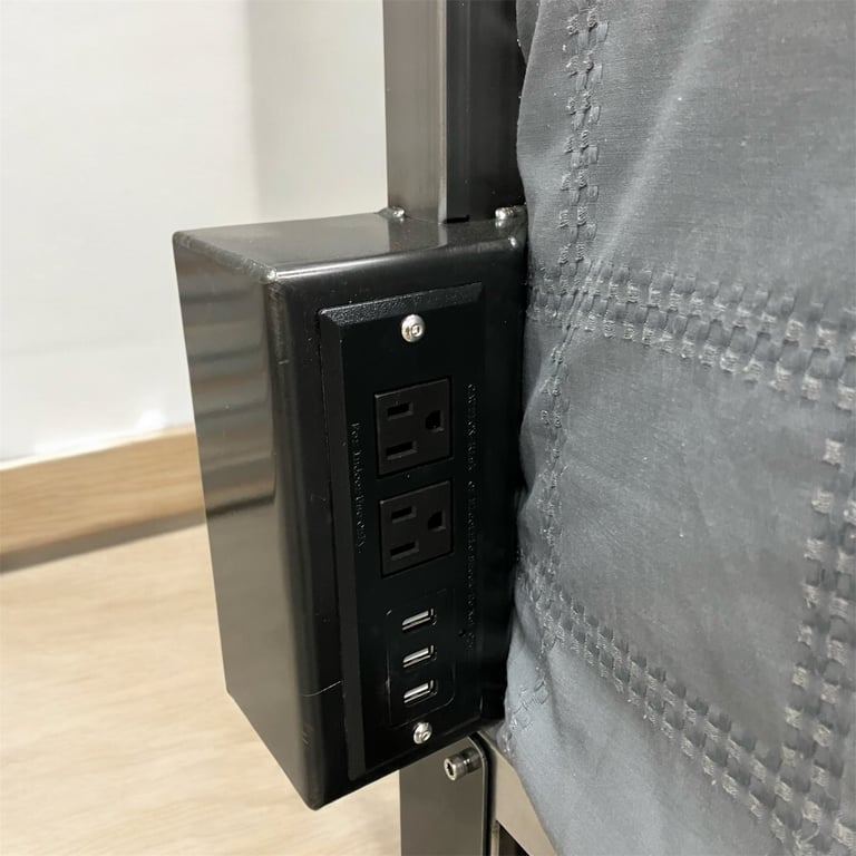 Black wall outlet with USB ports and power sockets mounted on gray drywall with wood flooring visible below