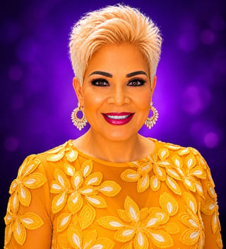 Woman with short blonde hair wearing yellow floral top and gold earrings, smiling against purple background