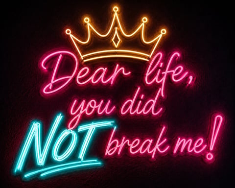 Neon sign with golden crown and text reading Dear life, you did NOT break me! in pink and blue lights